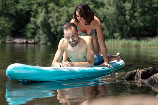 CREATIVE - Paar am See in Berlin Berlin, Deutschland - 25. Juli 2023: (CREATIVE) Ein Mann und eine Frau (Models) genießen auf einem SUP (stand up paddle boat) einen Sommertag an der Krummen Lanke, einem See in Berlin. Berlin