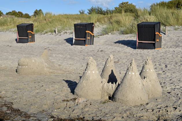 10 08 2023 island Poel beach art Germany Mecklenburg Vorpommern island Poel Baltic Sea coast on the beach sand beach art left a fish whale formed from sand the eyes and teeth are made of shells right a sand castle behind it three brown beach chairs