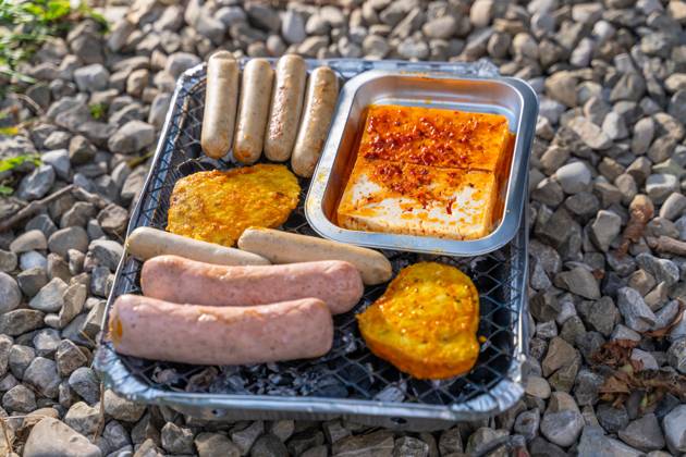 Bavaria, Germany - 2 September 2023: Vegetarian Grilling, Bratwurst Vegan and Vegetarian on a disposable grill on pebbles next to a meadow. Meat and sausage substitutes