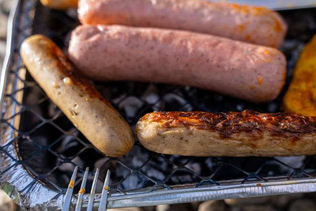 Bavaria, Germany - 2 September 2023: Vegetarian Grilling, Bratwurst Vegan and Vegetarian on a disposable grill on pebbles next to a meadow. Meat and sausage substitutes