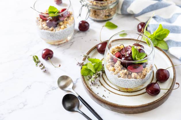Healthy menu concept. Home made granola breakfast. Glass of parfait made of granola, berries cherry, yogurt with chia seeds on rustic table. Copy space. Healthy menu concept. Home made granola breakfast. Glass of parfait made of granola, berries cherry, yogurt with chia seeds on rustic table. Copy space. Copyright: xZoonar.com ELENAxHRAMOVAx 20052402