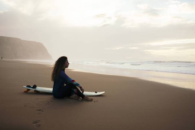 Thoughtful woman with surfboard sitting at beach model released, Symbolfoto, DCRF01769
