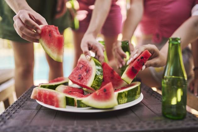 Hands of friends holding slices of watermelon at table model released, Symbolfoto property released, ANNF00419