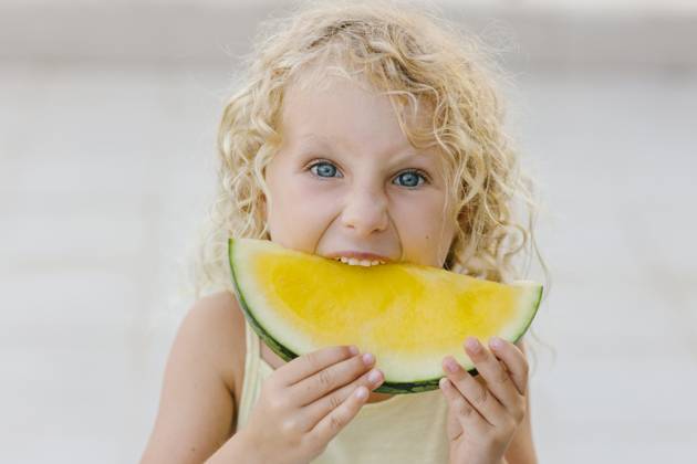 Blond girl biting slice of yellow watermelon model released, Symbolfoto, SIF00807