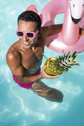 Happy man holding pineapple and swimming in water model released, Symbolfoto, VRAF00193