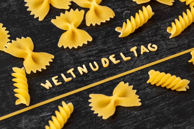 Augsburg, Bavaria, Germany - 19 October 2023: World Noodle Day word formed from letter noodles amidst various noodle varieties. Symbol image World Noodle Day on 25 October