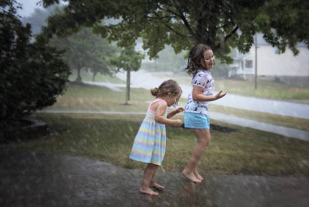 Sisters jumping in puddles during summer rain Wooster, Ohio, United States CR_JOKU231022-1268193-01 ,model released, Symbolfoto