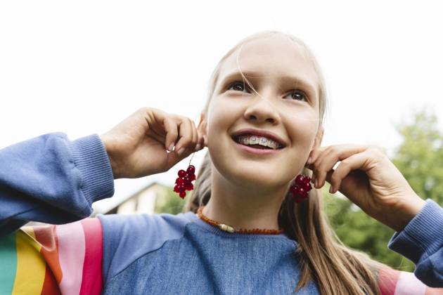 Smiling girl holding fresh redcurrants near ears model released, Symbolfoto, EYAF02846