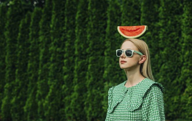 Woman wearing sunglasses standing with watermelon on head in garden model released, Symbolfoto, VSNF01092