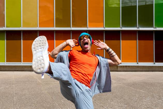 Joyful man dancing energetically in front of a multicolored windowed building Model Released SergioVictorVega_ID16857_514943_015 Copyright: xSergioxVictorxVegax