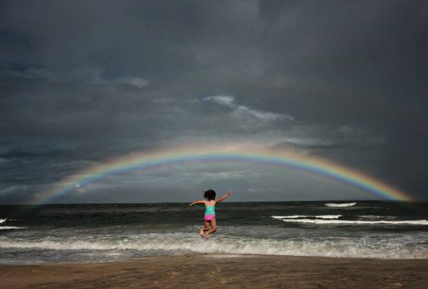 Young girl jumping in the ocean under rainbow Avon, North Carolina, United States CR_JOKU231105-1281095-01 ,model released, Symbolfoto
