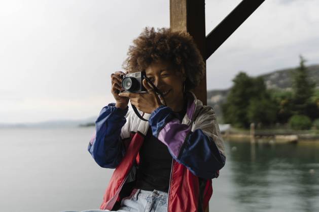 Smiling young woman photographing with camera near lake model released, Symbolfoto, BOYF02034