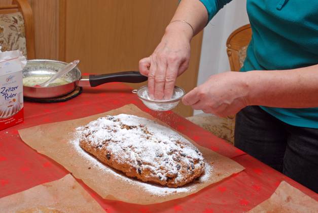 15 12 2013 Baking stollen Germany Saxony Anhalt Altmark Altmarkkreis Salzwedel Kusey Stollen baking ready-baked quark stollen are placed on baking paper in the kitchen to cool before they are finally spread with melted butter and sprinkled with sugar and powdered sugar