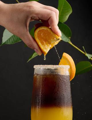 Iced coffee with orange juice in a transparent glass, a woman s hand squeezes an orange slice into a bubble drink Iced coffee with orange juice in a transparent glass, a woman s hand squeezes an orange slice into a bubble drink Copyright: xZoonar.com DANKOxNx 20557539