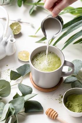 A vertical shot of Green tea latte with milk in a white cup with green leaves and wooden spoon 201079 RECORD DATE NOT STATED