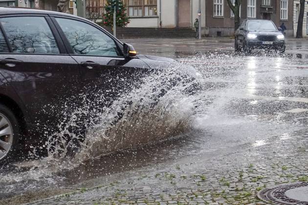21 12 2023, Berlin, GER car driving on a road through a big puddle everyday life, cropping, aquaplaning, exterior, exterior shot, auto