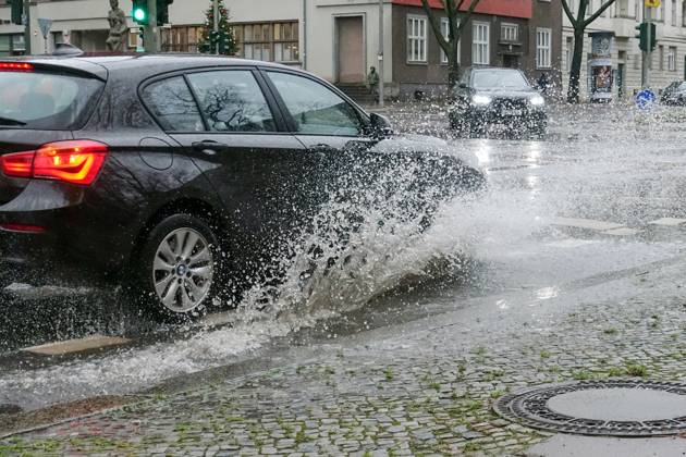21 12 2023, Berlin, GER car driving on a road through a big puddle everyday life, cropping, aquaplaning, exterior, exterior shot, auto