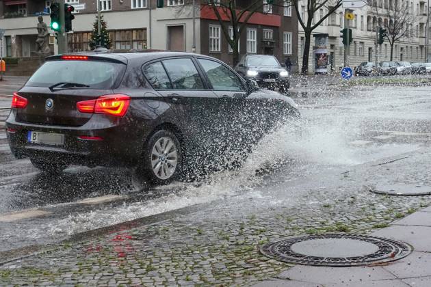 21 12 2023, Berlin, GER car driving on a road through a big puddle everyday life, aquaplaning, exterior, exterior shot, automobiles, cars, car tr