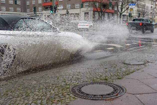21 12 2023, Berlin, GER car driving on a road through a big puddle everyday life, cropping, aquaplaning, exterior, exterior shot, auto