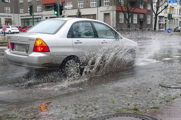 21 12 2023, Berlin, GER car driving on a road through a big puddle everyday life, aquaplaning, exterior, exterior shot, automobiles, cars, car tr