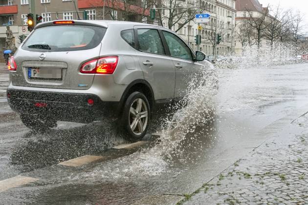 21 12 2023, Berlin, GER car driving on a road through a big puddle everyday life, aquaplaning, exterior, exterior shot, automobile, car, car traffic