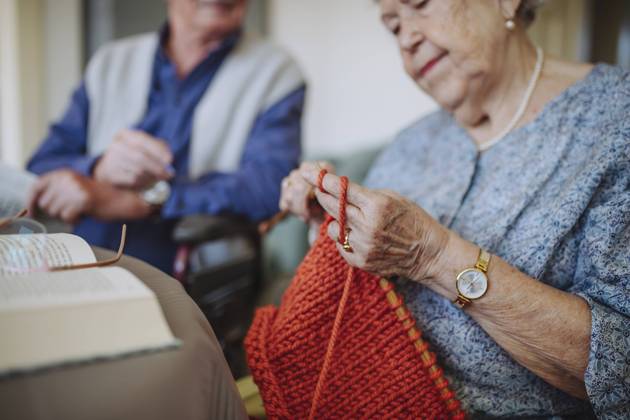 Senior woman knitting wool with man sitting in background model released, Symbolfoto property released, HAPF03269