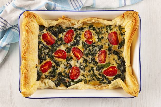 Home made spinach quiche top view. Vegetarian spinach pie or quiche with cheese and tomatoes in a baking dish from above. Copyright: xZoonar.com Eskymaks.x 16311478