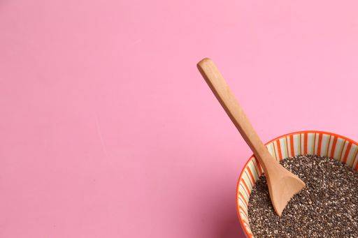 A closeup of a bowl filled with chia seeds, with a wooden spoon on a pink surface 712840 RECORD DATE NOT STATED