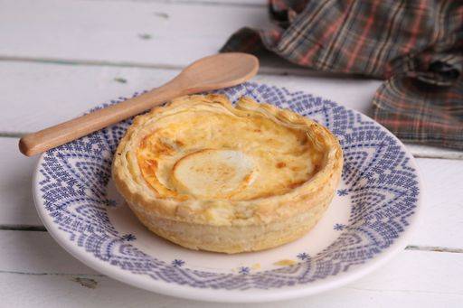 A closeup of a delicious three cheese quiche next to a wooden spoon on a plate 713162 RECORD DATE NOT STATED
