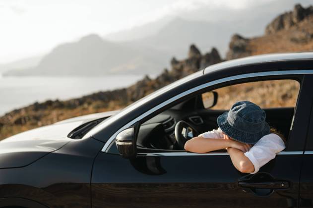 Young woman leaning on car window looking at coastal landscape Foinikas, Greece R_AKAO240102E3-1313979-01 ,model released, Symbolfoto