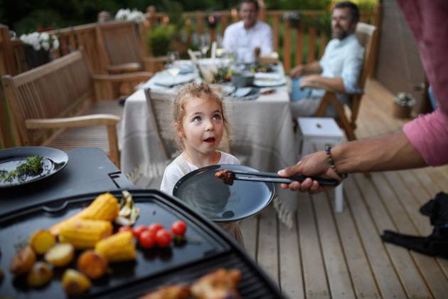 Father putting grilled meat and vegetable on plate to his daughter during family summer garden party. A father putting grilled meat and vegetable on plate to his daughter during family summer garden party. model released Copyright: xx HHH FAMILY GRILL BODOVCI 2022 HHH 171
