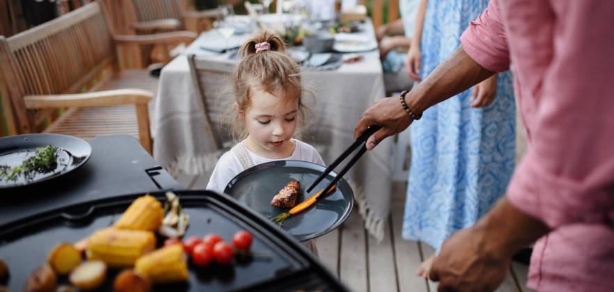 Father putting grilled meat and vegetable on plate to his daughter during family summer garden party. A father putting grilled meat and vegetable on plate to his daughter during family summer garden party. model released Copyright: xx HHH FAMILY GRILL BODOVCI 2022 HHH 173