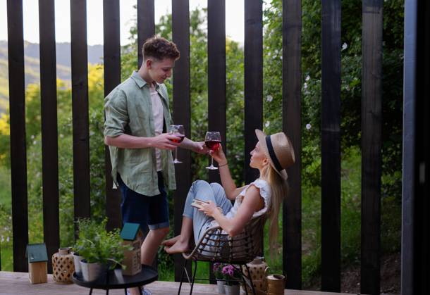 Young couple clinking with wine outdoors, weekend away in tiny house in countryside, sustainable living. A young couple clinking with wine outdoors, weekend away in tiny house in countryside, sustainable living. model released Copyright: xx HHH TINY HOUSE LIVING 2022 HHH 325