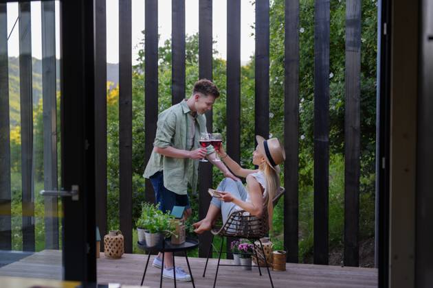 Young couple clinking with wine outdoors, weekend away in tiny house in countryside, sustainable living. A young couple clinking with wine outdoors, weekend away in tiny house in countryside, sustainable living. model released Copyright: xx HHH TINY HOUSE LIVING 2022 HHH 333