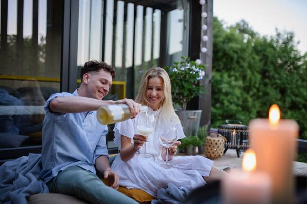 Young couple clinking with wine outdoors, weekend away in tiny house in countryside, sustainable living. A young couple clinking with wine outdoors, weekend away in tiny house in countryside, sustainable living. model released Copyright: xx HHH TINY HOUSE LIVING 2022 HHH 511