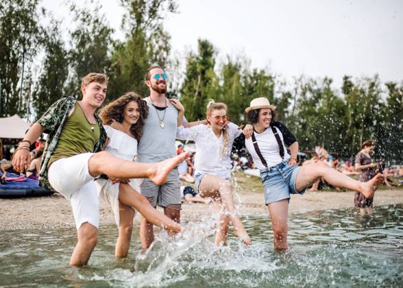 Group of young friends at summer festival, standing in lake. Group of young friends at summer festival, standing in lake and splashing water. model released Copyright: xx Uprising_2019_1552