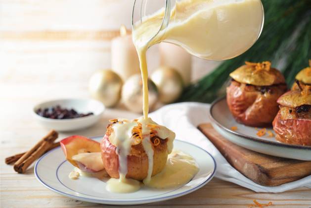 Pouring vanilla sauce on a baked apple filled with almonds, honey and raisins, homemade winter dessert for holidays like Christmas, Thanksgiving or new year, copy space, selected focus Pouring vanilla sauce on a baked apple filled with almonds, honey and raisins, homemade winter dessert for holidays like Christmas, Thanksgiving or new year, copy space, selected focus Copyright: xZoonar.com MarenxWinterx 20987840