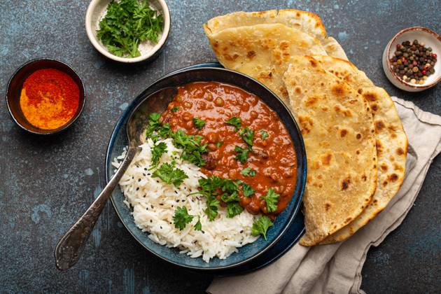 IMAGO Creative, Food, Brot, Naan Traditional Indian Punjabi dish Dal makhani with lentils and beans in black bowl served with basmati rice, naan flat bread, fresh cilantro and spoon on blue concrete rustic table top view Traditional Indian Punjabi dish Dal makhani with lentils and beans in black bowl served with basmati rice, naan flat bread, fresh cilantro and spoon on blue concrete rustic table top view. Copyright: xZoonar.com OlenaxYeromenkox 21076943