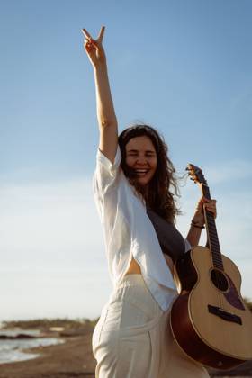 IMAGO Creative, Jahreszeit Sommer, Sommerferien Woman musician sings and plays guitar on the beach. In a bandana. Bali Kuta, Bali, Indonesia CR_YUKI240206-1331627-01 ,model released, Symbolfoto