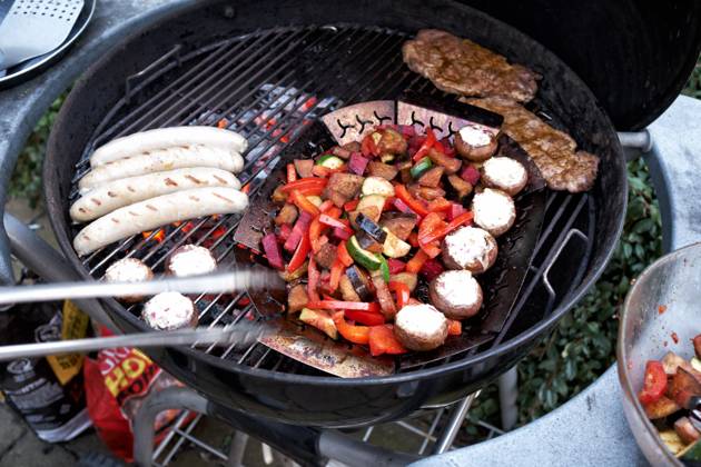 Barbecue at a Round grill become simultaneously Sausages, Steaks and Vegetables grilled Food NRW