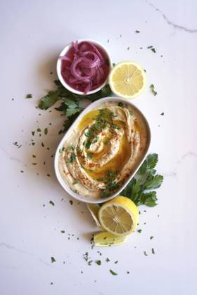 Chickpea hummus served with olive oil, pickled red onion, lemons, and flatbread on a white marble table background. Minimal layout flatlay. Chickpea hummus served with olive oil, pickled red onion, lemons, and flatbread on a white marble table background. Minimal layout flatlay. Copyright: xMilleflorexImagesx MIL150124-22