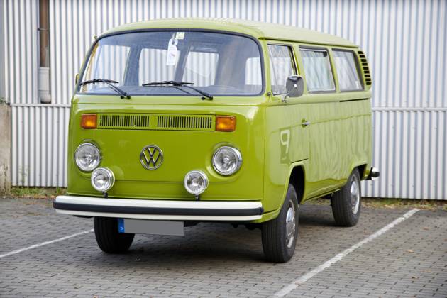 Oldtimer VW Bulli T2 a Very Maintained Grasshopper gruener VW Bulli T2 is at a marked Car park before a white Corrugated iron wall Food