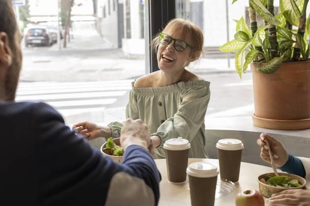 Cheerful businesswoman sharing lunch with colleague in cafeteria at workplace model released, Symbolfoto property released, JCCMF11199