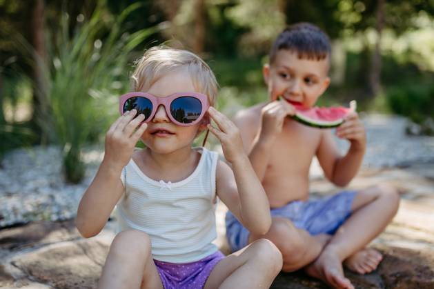 Little chidren sitting near lake and eating watermelon on hot sunny day during summer vacation. Little chidren sitting near a lake and eating watermelon on hot sunny day during summer vacation. model released