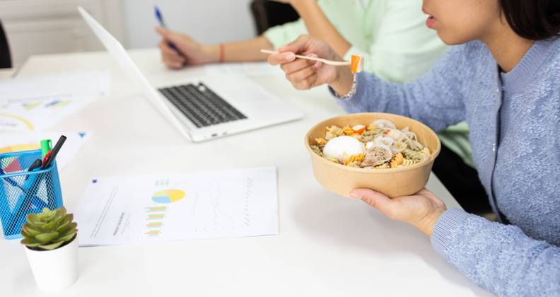 A person enjoys a healthy bowl of noodles with vegetables and egg during a busy workday, promoting productivity and well-being. Model Released DavidMunoz_ID19491_576509_063 Copyright: xDavidxMunozx