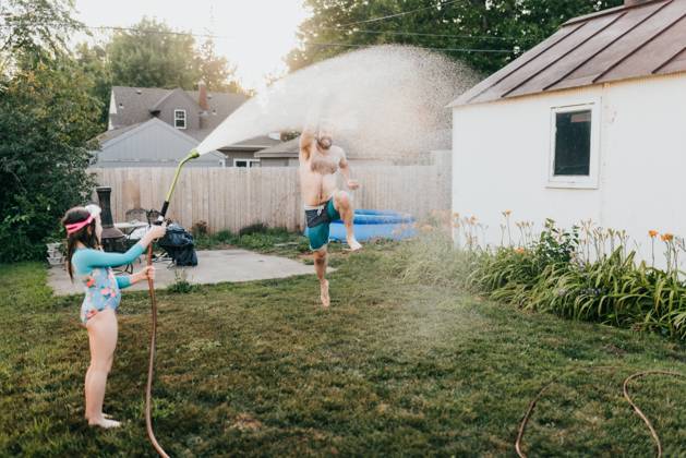 Young girl holds garden hose while dad runs through water Sioux Falls, South Dakota, United States CR_ASWE240317-1369124-01 ,model released, Symbolfoto ,property released