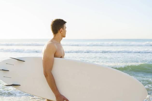 Young man carrying surfboard and looking at sea model released, Symbolfoto, AAZF01671
