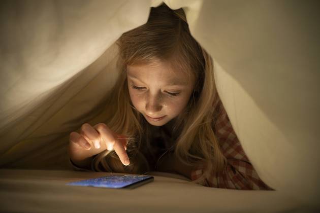 Creative Highlights Symbolbilder Girl using smart phone under blanket on bed at home model released, Symbolfoto property released, NJAF00878