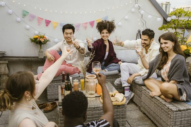 Group of multiracial friends toasting drinks while sitting together in balcony Germany, Berlin, model released, property released Copyright: xMaskotx , MA108150 MA108150