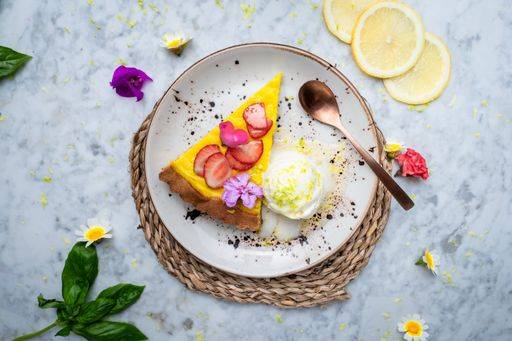 A plate with Vegan No-bake cheesecake topped with strawberry on the side cashew cream. Served on a plate with fruits around. 23149080 RECORD DATE NOT STATED